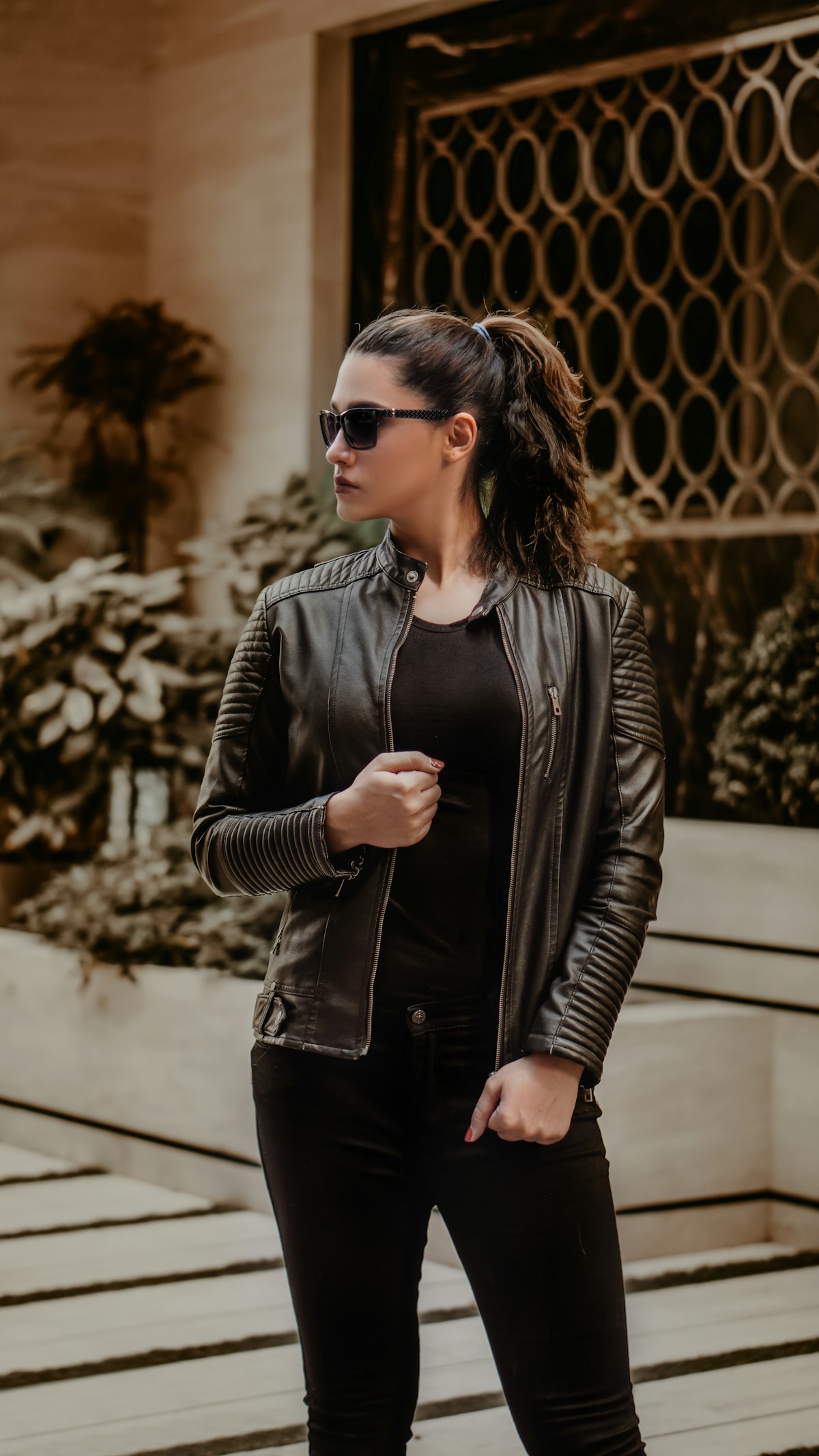 Female model in a black leather jacket with sunglasses — editorial fashion